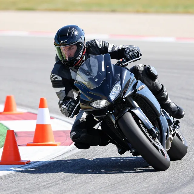 Vue de face d'un motard en plein virage sur un circuit d'entraînement au permis moto.