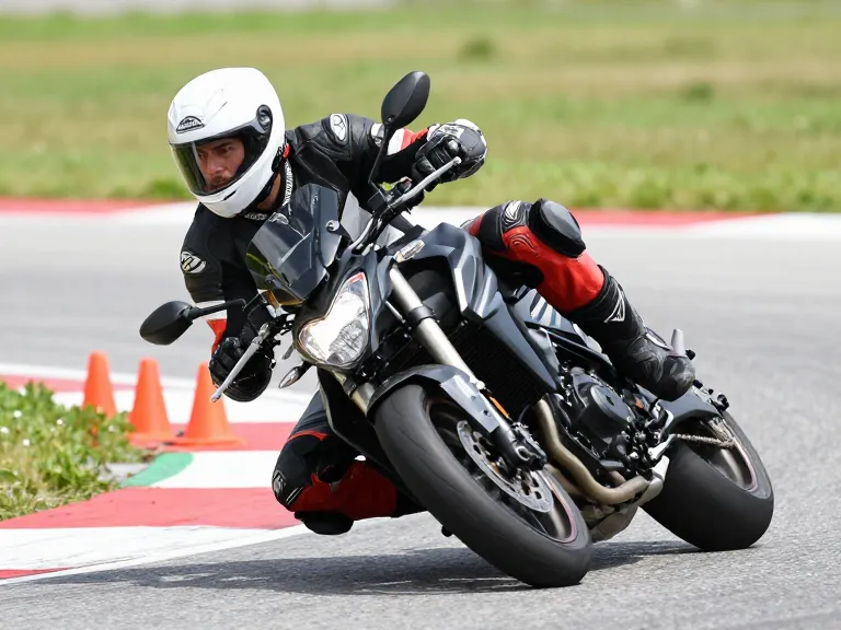 Élève motard en pleine inclinaison sur un plateau technique tournant la tête pour viser la sortie du virage.
